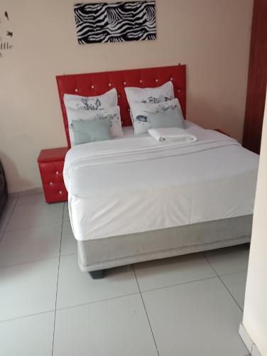 una camera con un grande letto con testiera rossa di Rizhatchguest a Mahikeng