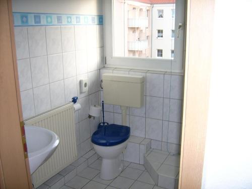 La salle de bains est pourvue de toilettes avec un siège bleu. dans l'établissement Pension Regenbogen, à Stralsund
