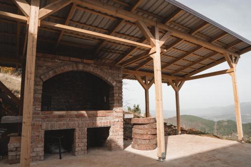 an outdoor brick fireplace with a wooden roof at Vila Suvo vrelo sa unutrašnjim bazenom i saunom Jahorina in Jahorina