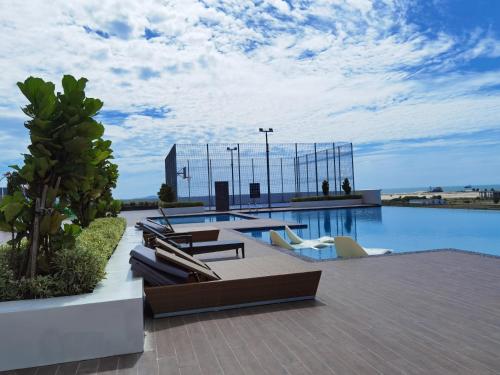 een resort met een zwembad met stoelen en uitzicht bij Amber Cove Seaview I MUJI 2BR I Game Room I 3-9pax in Melaka