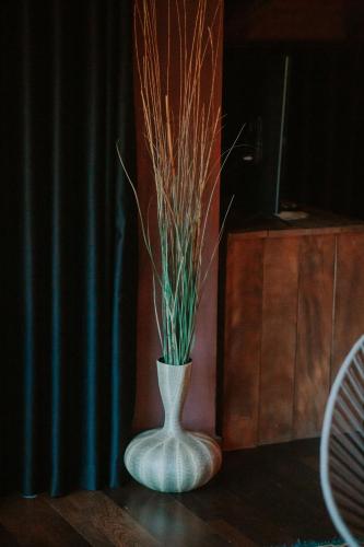 a white vase with grass in it on a table at Dim's Hotel & Restaurant in Korçë