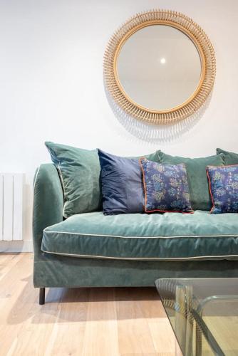 - un canapé vert dans le salon avec un miroir dans l'établissement Fully equipped duplex with exterior and parking !, à Lille