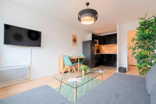 een woonkamer met een bank en een tafel bij Lille, fully-equipped apartment with parking space in Lille