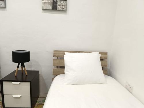 a bedroom with a white bed with a wooden headboard at San Francisco Studios Valletta in Il-Furjana