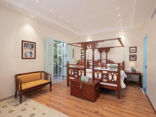 Villa Kouga في بونديتْشيري: غرفة نوم مع سرير مظلة كبيرة وكرسي