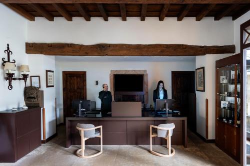 two people standing in a room with a desk and chairs at Parador de Cangas de Onís in Villanueva de Cangas de Onís