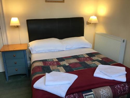 a bedroom with a bed with two towels on it at The Royal Crown Guest House in Aberdeen