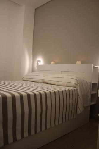 a white bedroom with a bed with a striped blanket at Lasso B&B in Corigliano Calabro