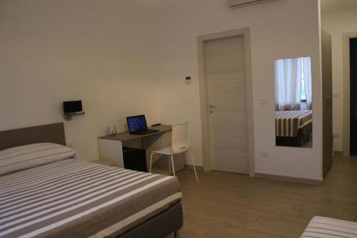 a bedroom with a bed and a desk with a laptop at Lasso B&B in Corigliano Calabro