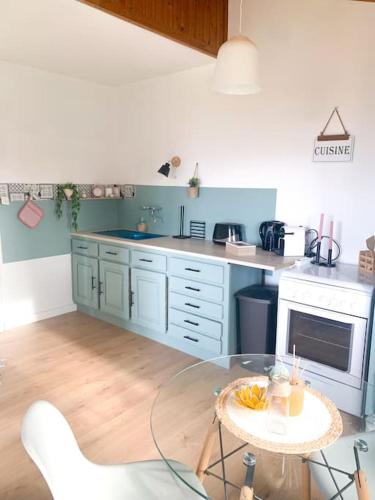 une cuisine avec des armoires bleues et une table en verre dans l'établissement la maison du vignoble, à La Limouzinière