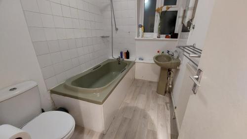 a bathroom with a green tub and a sink at 2-Bed Apartment in King's Cross Central London in London