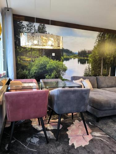 un salon avec un canapé et un tableau représentant un lac dans l'établissement Harz-High-End-Ferienwohnung-Nicholas, à Hahnenklee