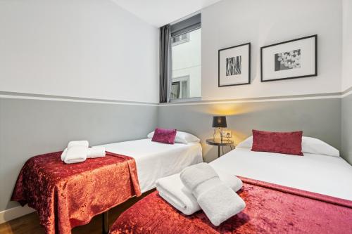 a bedroom with two beds with red and white sheets at Sensation Sagrada Familia in Barcelona