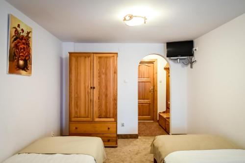 a bedroom with two beds and a tv and a door at Willa Pod Orłem Jacuzzi Sauna in Kościelisko