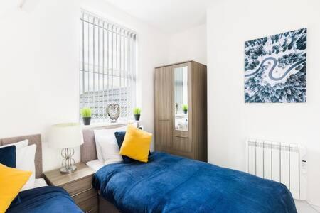 a bedroom with two beds with blue sheets and yellow pillows at Sapphire Suite Moseley Mews by StayStaycations in Birmingham