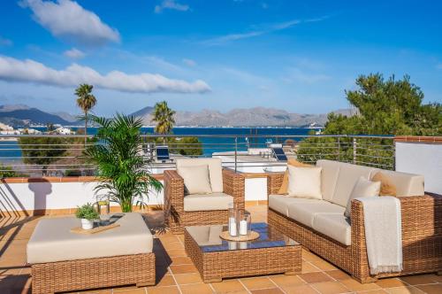 um pátio com mobiliário de vime e vista para a água em Traumhafte Villa Marisol für 8 Gäste am Meer em Alcudia