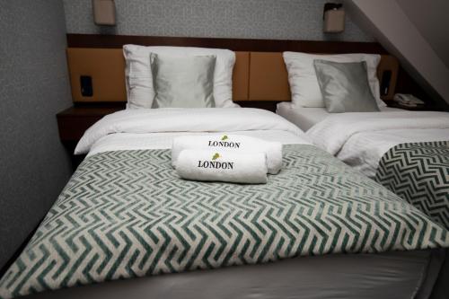 two beds in a hotel room with towels on them at LONDON Boutique hotel & Restaurant in Trnava