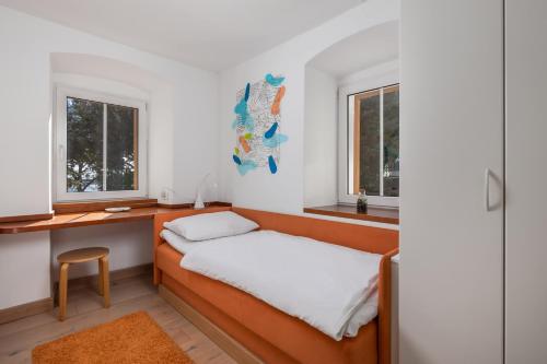 a bed in a room with a desk and windows at Apartments Anaika at the beach, Opatija in Ika