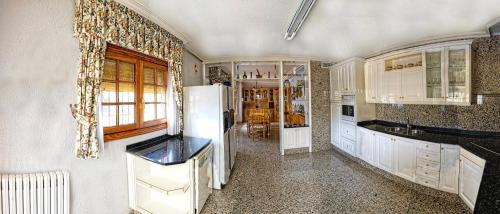 a kitchen with white cabinets and a refrigerator at El Carrascal in Caravaca de la Cruz