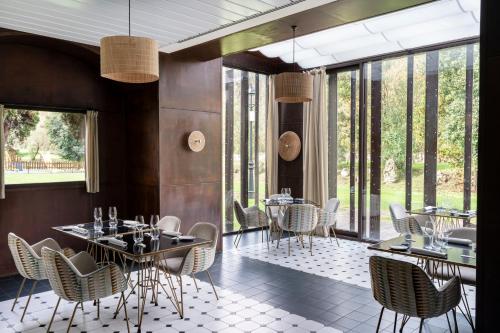 a restaurant with tables and chairs and large windows at Parador de Cangas de Onís in Villanueva de Cangas de Onís