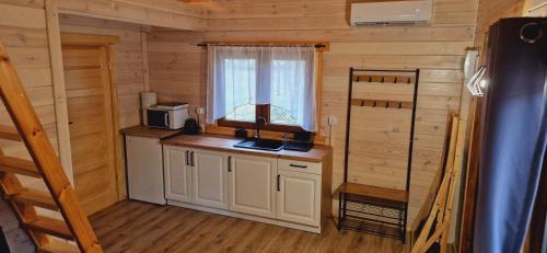 una cocina con fregadero y una ventana en una cabaña de madera en BORSKIE CHATKI en Borsk