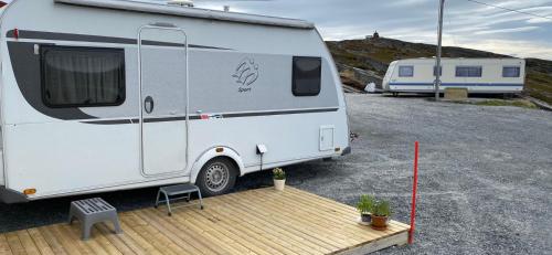 een witte caravan geparkeerd op een parkeerplaats bij Repvåg Overnatting Nordkapp in Repvåg