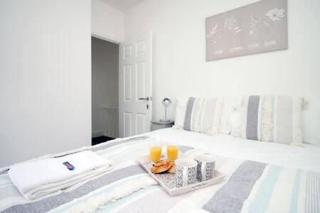 een bed met een dienblad met eten en twee glazen sinaasappelsap bij Norton Views by Afan Valley Escapes in Port Talbot