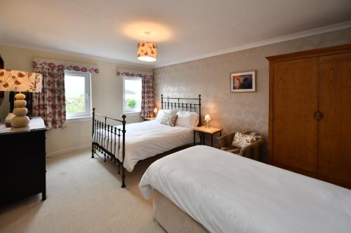 a bedroom with two beds and two windows at Lochans Lodge in Stranraer
