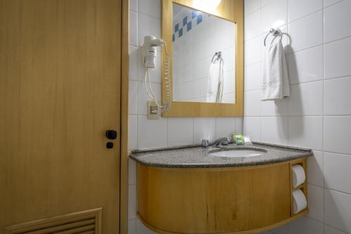 a bathroom with a sink and a mirror at Brivali Hotel Centro in Caçador