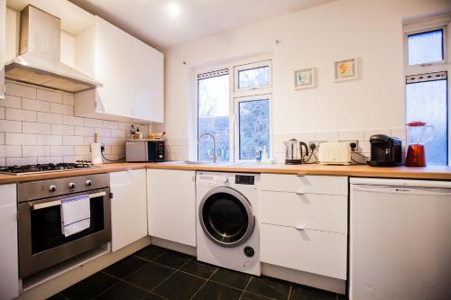 a kitchen with white cabinets and a washer at Richmond Modern Apartment in Richmond upon Thames