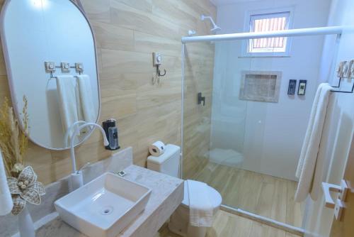 a white bathroom with a sink and a shower at Topázio Pousada in Morro de São Paulo