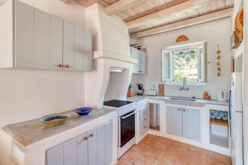a kitchen with white cabinets and a window at Lefkes Village Living in Lefkes