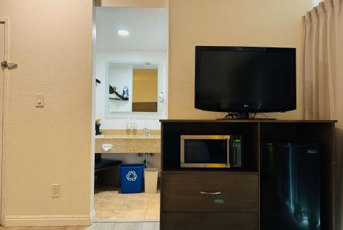 a bathroom with a tv on a cabinet with a television on it at Ramada by Wyndham San Diego Airport in San Diego