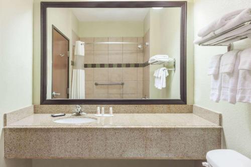 La salle de bains est pourvue d'un lavabo et d'un miroir. dans l'établissement Baymont by Wyndham Tyler, à Tyler