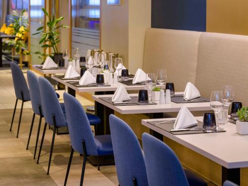 a row of tables with chairs and napkins on them at Mercure Hotel Duisburg City in Duisburg
