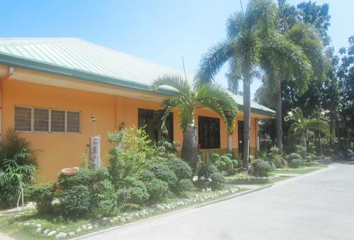 un edificio con árboles y plantas delante de él en RedDoorz @ Farm Side Hotel Laoag City en Laoag