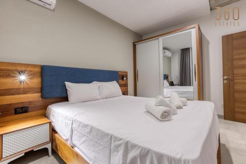 a bedroom with a large bed with towels on it at The Swieqi Poolside Suites in Is-Swieqi