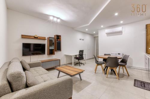 a living room with a couch and a table at The Swieqi Poolside Suites in Is-Swieqi