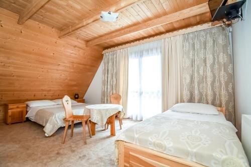 a bedroom with two beds and a table and a window at Willa Pod Orłem Jacuzzi Sauna in Kościelisko