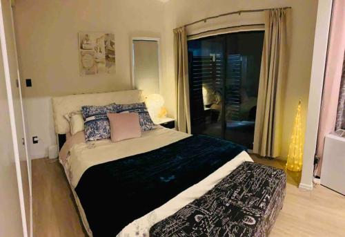 a bedroom with a bed with pillows and a window at Delightful little house & Chateau Charme Suite in Auckland