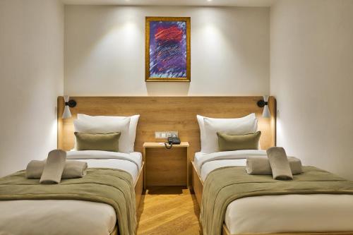two beds in a room with a painting on the wall at Joyway Hotels Istanbul Sultanahmet in Istanbul