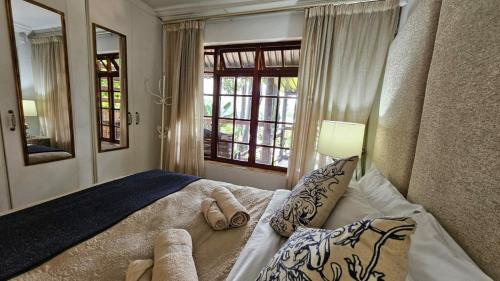 ein Schlafzimmer mit einem Bett mit Kissen und einem Fenster in der Unterkunft Pont de Fleur in Hartbeespoort