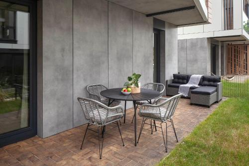 a patio with a table and chairs and a couch at Apartamenty na Półwyspie Wydma&Las in Jastarnia