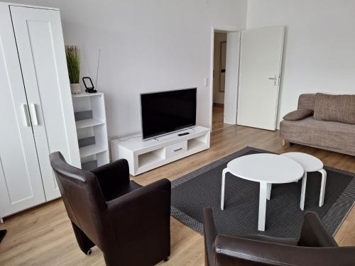 ein Wohnzimmer mit einem TV, einem Tisch und Stühlen in der Unterkunft Helle 3 Zimmer Wohnung in Krefeld