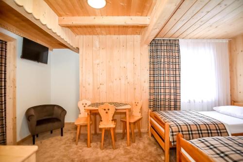 a bedroom with a table and a bed and a desk at Willa Pod Orłem Jacuzzi Sauna in Kościelisko