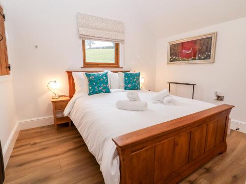 a bedroom with a large white bed with blue pillows at Rockhill Farm Hay Barn in Craven Arms