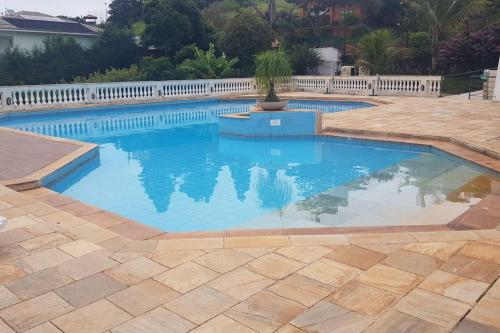 a swimming pool with blue water and a fence at Piemonte Flat Serra Negra in Serra Negra