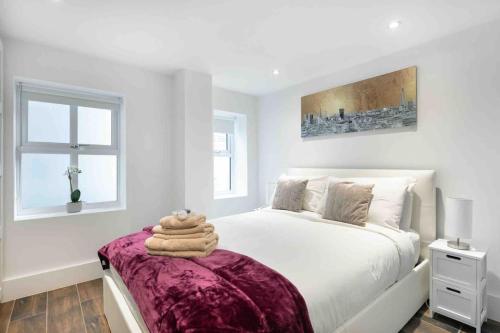 - une chambre blanche avec un grand lit et une couverture violette dans l'établissement Luxury 1 bed apartment - Wanstead Village, à Londres