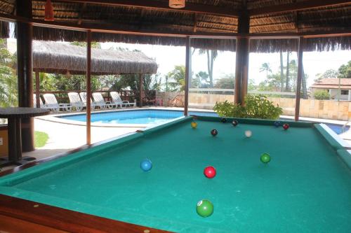 a pool table with balls on it next to a swimming pool at Pousada Corais do Sul in Pipa