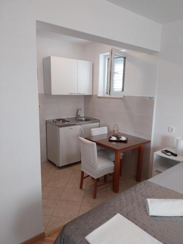 a small kitchen with a table and chairs and a sink at Apartments Rose Loboja in Makarska